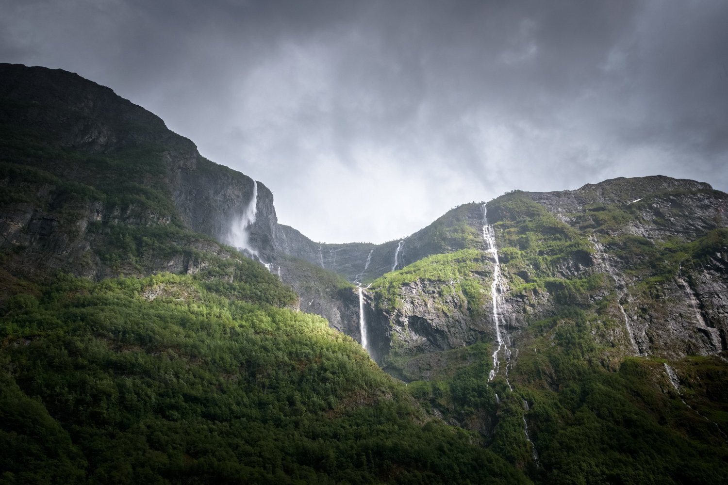 Waterfalls falling down sheer cliffs into cold fjord water in Norway